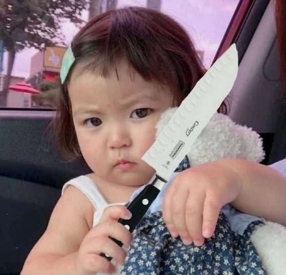 Meme em bé cầm đồ vật như dao dọa dẫm với vẻ mặt tinh nghịch